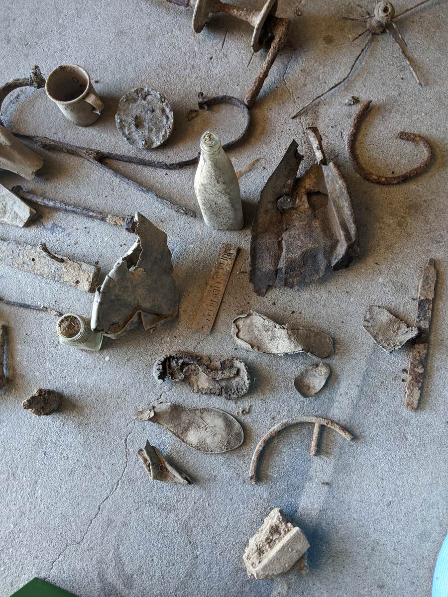 Surface finds laid out for recording, including bottles, shoe soles, and metal objects.