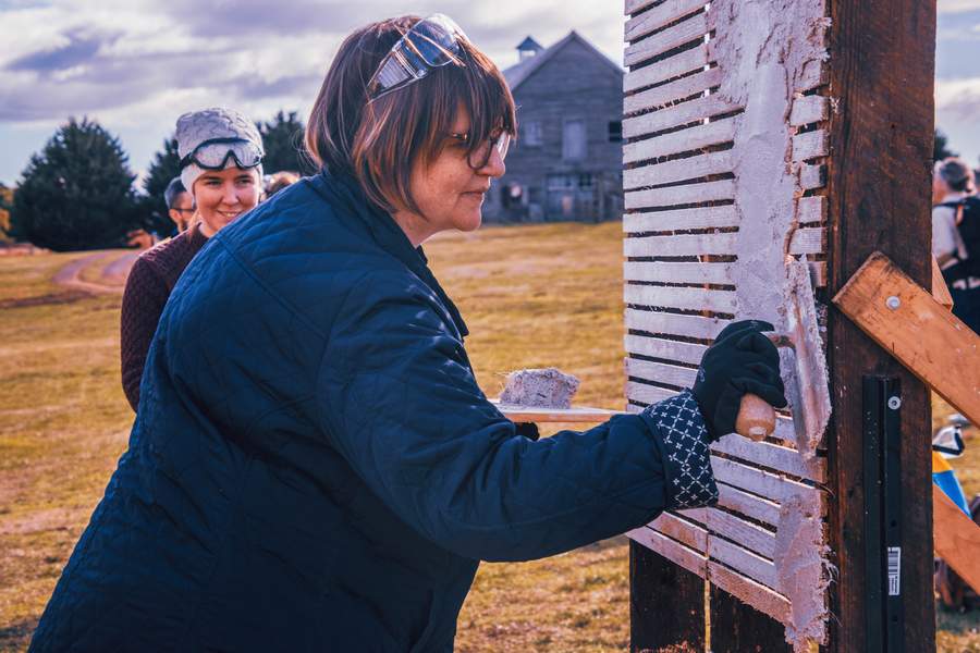 Nicci applying lime plaster to timber shutters at Longford Academy, 2025.